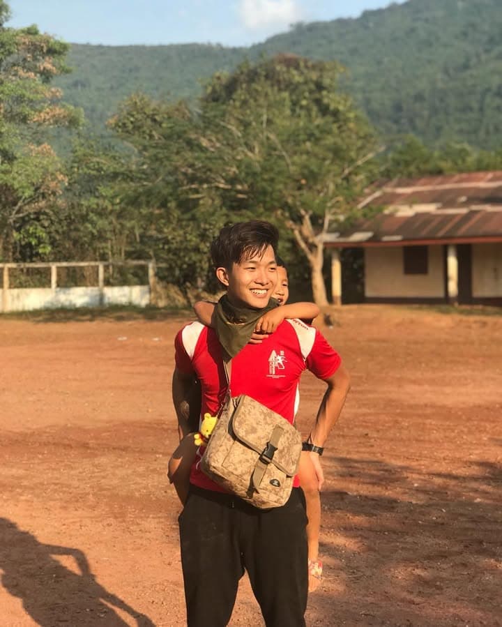 Joel carrying a child on the school field in Nong Luang Village, Laos